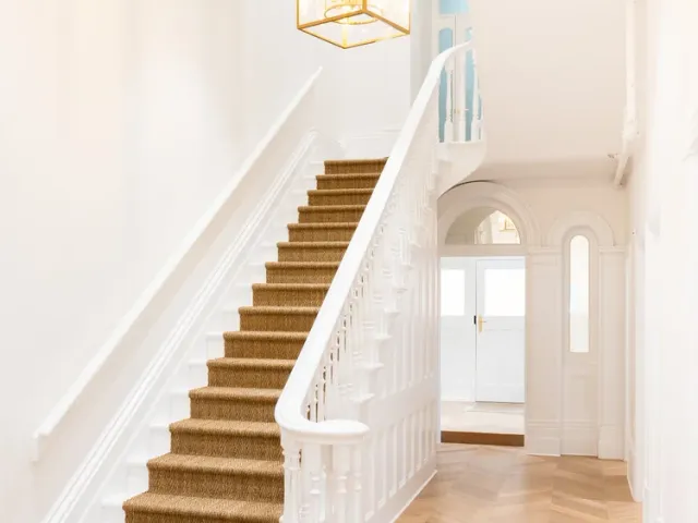 The entrance hall at Davaar House, with its white staircase, brass lantern and herringbone timber floor